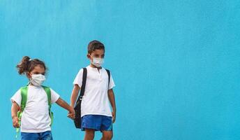 crianças vestindo face protetora mascarar indo costas para escola durante corona vírus pandemia - cuidados de saúde e Educação conceito foto