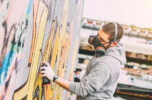 rua artista pintura colorida grafite em uma parede debaixo a ponte - urbano homem realizando com murales - conceito do moderno arte - foco em dele mão foto