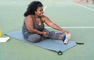 cheio de curvas afro mulher fazendo alongamento exercícios sessão - jovem africano fêmea tendo Diversão Treinamento ao ar livre - desportivo pessoas estilo de vida conceito foto