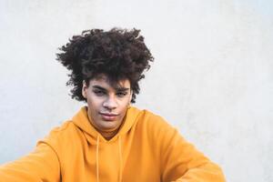 afro sorridente homem retrato - misturado raça jovem cara com encaracolado cabelo posando dentro frente Câmera - juventude milenar geração cultura e multirracial pessoas conceito foto