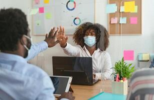 jovem africano pessoas dentro co-trabalho criativo espaço vestindo cirúrgico mascarar proteção e guardando social distância para evitar corona vírus espalhar - saúde Cuidado e o negócio tecnologia conceito foto