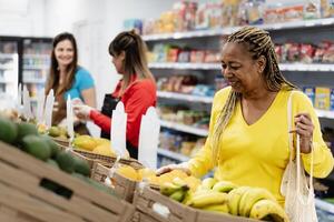 Senior africano mulher comprando fresco frutas dentro supermercado foto