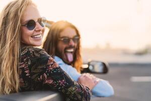 feliz jovem casal tendo Diversão fazendo estrada viagem com na moda conversível carro - relação e juventude período de férias estilo de vida conceito foto