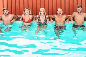 feliz amigos desfrutando verão dia dentro natação piscina - jovem pessoas tendo Diversão dentro exclusivo privado villa - juventude período de férias estilo de vida conceito foto