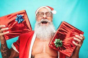 feliz santa claus segurando Natal presente - hipster em forma Senior tendo Diversão a comemorar x-mas feriados - idosos pessoas e tradicional estilo de vida cultura foto