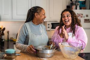 feliz africano mãe e filha preparando uma caseiro sobremesa foto