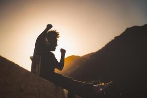 afro homem tendo Diversão dançando e ouvindo música com fones de ouvido e vintage boombox estéreo às pôr do sol Tempo durante Férias foto