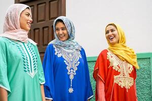 feliz muçulmano mulheres caminhando dentro a cidade - árabe adolescente meninas tendo Diversão ao ar livre - conceito do pessoas, cultura e religião foto