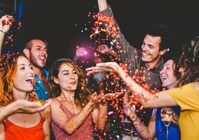 feliz amigos fazendo festa jogando confete dentro a clube - milenar jovem pessoas tendo Diversão a comemorar dentro a Boate - vida noturna, entretenimento e juventude festivo feriados conceito foto