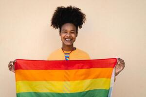 feliz africano gay mulher a comemorar orgulho segurando arco Iris bandeira ao ar livre - lgbt conceito foto