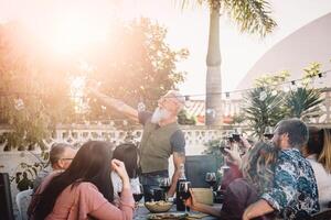 feliz família levando selfie com Móvel Smartphone Câmera às jantar festa ao ar livre - pessoas com diferente idades e etnia comendo juntos em pátio - Comida e bebida, aposentado e jovem pessoas conceito foto