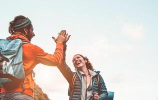 feliz amigos empilhamento mãos enquanto fazendo caminhada excursão em montanha - jovem turistas caminhando e explorando a selvagem natureza - caminhante, equipe, caminhar e viagem pessoas conceito foto