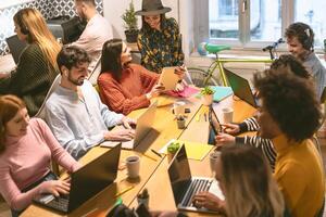 feliz jovem pessoas trabalhando juntos dentro escritório - multirracial amigos tendo Diversão dentro coworking espaço - juventude colegas de trabalho milenar geração e tecnologia área de trabalho conceito foto