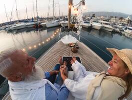 Senior casal em barco a vela período de férias - feliz idosos pessoas tendo Diversão a comemorar Casamento aniversário em barco viagem - amor relação e viagem estilo de vida conceito foto