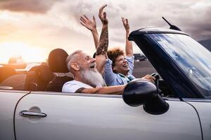 feliz Senior casal tendo Diversão dirigindo em Novo conversível carro - maduro pessoas desfrutando Tempo juntos durante estrada viagem Tour período de férias - viagem pessoas estilo de vida conceito foto