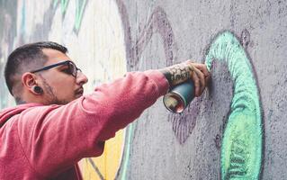 rua grafite artista pintura com uma cor spray pode mural grafite em a parede dentro a cidade - urbano e moderno rua arte estilo de vida conceito foto