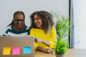 afro mãe e filha tendo Diversão usando computador para compras conectados - juventude e idosos pessoas com tecnologia conceito foto