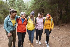 grupo do mulheres com diferente idades e etnias tendo Diversão caminhando dentro nebuloso floresta - aventura e Viajantes pessoas conceito foto