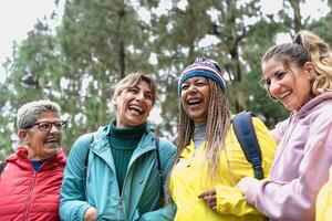 grupo do mulheres com diferente idades e etnias tendo Diversão caminhando dentro a madeiras - aventura e viagem pessoas conceito foto