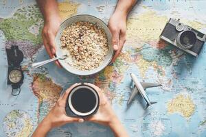 topo Visão mãos pessoas planejamento período de férias com mundo mapa enquanto fazendo café da manhã com cereal leite - casal obtendo pronto para Próximo mundo Tour - conceito do aventura, turismo, e viajando pessoas estilo de vida foto