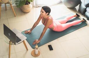 jovem latim mulher fazendo pilates virtual ginástica classe com computador portátil às casa - e-learning e pessoas bem estar estilo de vida conceito foto