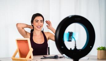 jovem mulher vlogging conectados com Smartphone cam e anel conduziu a partir de casa - milenar pessoas com social meios de comunicação e inteligente trabalhando conceito foto