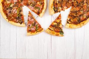 dois diferente delicioso ampla pizzas em uma luz de madeira fundo foto
