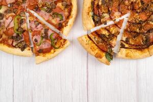 dois diferente delicioso ampla pizzas em uma luz de madeira fundo foto