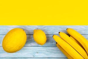 a sortimento do amarelo frutas mentiras em uma azul de madeira fundo e uma amarelo fundo foto