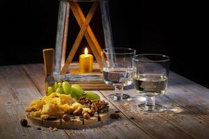 queijo prato com uma variedade do lanches em a mesa com dois óculos do vinho de luz de velas foto