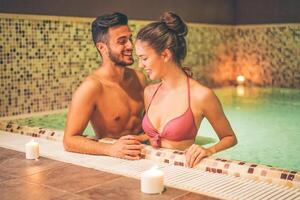 feliz casal relaxante dentro uma caloroso piscina hidro massagem às hotel spa. jovem amantes tendo Diversão dentro uma térmico banho. casal e bem ser conceito. suave saturado edição. foco em fêmea face foto