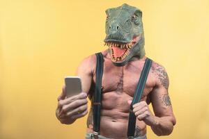 Senior homem levando selfie com Smartphone enquanto vestindo dinossauro mascarar - maduro social influenciador tendo Diversão com Móvel aplicativo - pessoas estilo de vida e tecnologia conceito foto