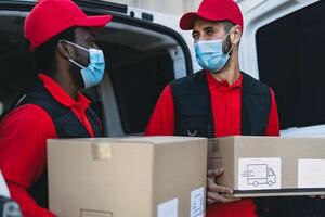 jovem Entrega homens carregando cartão caixa enquanto vestindo face mascarar para evitar corona vírus espalhar - pessoas trabalhando com velozes entregar durante corona vírus surto foto