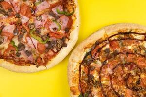 dois diferente delicioso grande pizzas em uma amarelo fundo foto