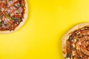 dois diferente delicioso grande pizzas em uma amarelo fundo foto