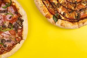 dois diferente delicioso grande pizzas em uma amarelo fundo foto