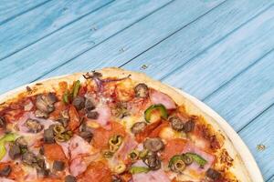 delicioso ampla pizza com vitela e cogumelos em uma azul de madeira fundo foto