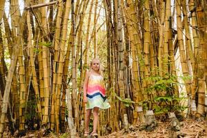 uma pequeno menina em a fundo do uma bambu Arvoredo dentro a botânico jardim do a ilha do Maurícia foto
