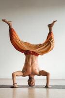 uma homem com uma nu tronco faz ioga em pé em dele cabeça dentro de casa. ginástica treinador foto