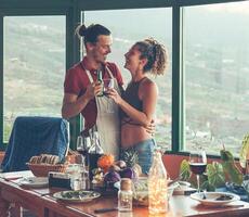 feliz casal brindar com Cerveja e vinho às jantar encontro - jovem amante comendo e bebendo juntos às casa - comida, amor e relação, juventude pessoas estilo de vida conceito foto