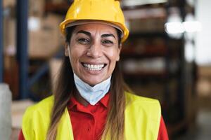 feliz latim mulher trabalhando dentro armazém enquanto vestindo face mascarar durante corona vírus pandemia - logístico e indústria conceito foto