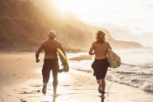 feliz em forma amigos tendo Diversão surfar em pôr do sol Tempo - surfistas pai e filho corrida Fora a oceano - desportivo saúde pessoas estilo de vida e extremo esporte conceito foto