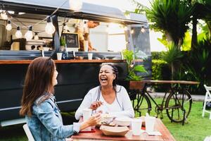 feliz multirracial Senior amigos tendo Diversão comendo dentro uma rua Comida caminhão mercado foto