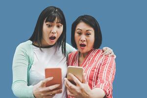 ásia mãe e filha usando Móvel smartphones ao ar livre - feliz chinês família tendo Diversão com Novo tendências tecnologia apps para social meios de comunicação - conceito do social pessoas vício com paternidade foto