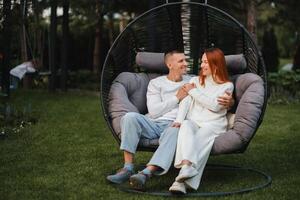 uma feliz família é sentado dentro uma maca em a gramado perto a casa foto