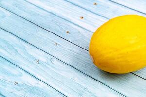 uma todo amarelo Melão mentiras em uma azul de madeira background.summer conceito foto