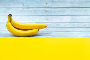 amarelo bananas mentira em uma azul de madeira fundo e uma amarelo fundo foto