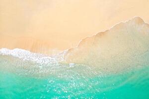 uma Visão a partir de uma altura do uma tropical de praia e ondas quebra em uma tropical dourado arenoso de praia. a mar ondas suavemente vento ao longo a lindo arenoso de praia foto