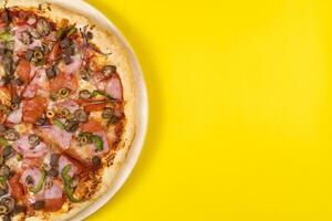 delicioso ampla pizza com vitela e cogumelos em uma amarelo fundo foto