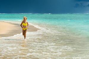 uma pequeno menina corre ao longo a de praia do a tropical ilha do Maurícia dentro a indiano oceano foto